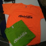 Camiseta técnica naranja con logo aniridia en negro y camiseta verde algodón con logo aniridia en blanco