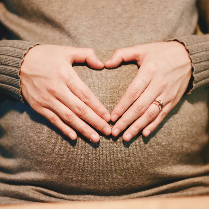 Manos en forma de corazón sobre tripa embarazada