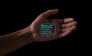 Una mano sobre fondo negro con un texto del AI Pin proyectado sobre la palma